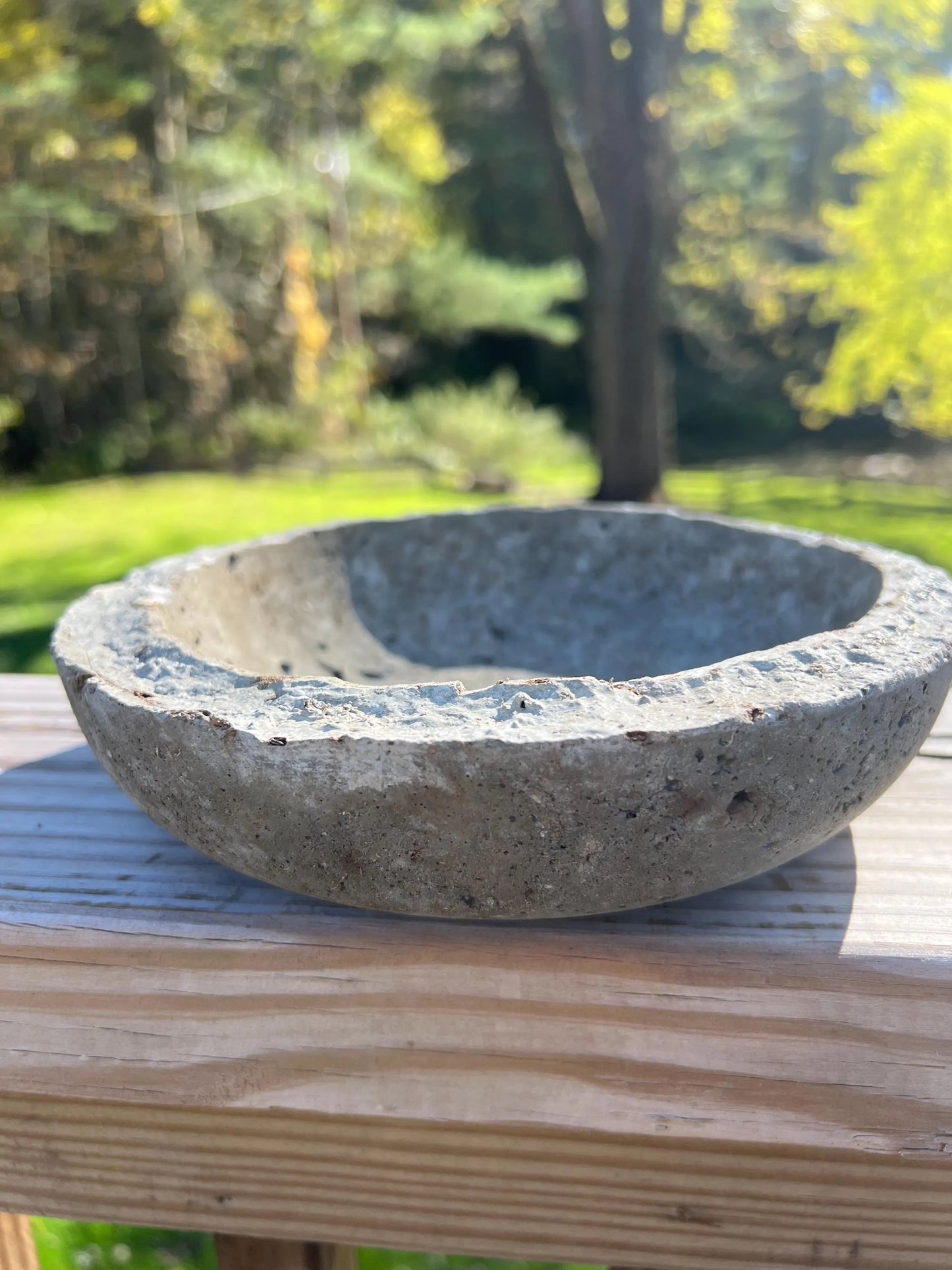 Concrete bowl on a wooden surface with a blurred natural background