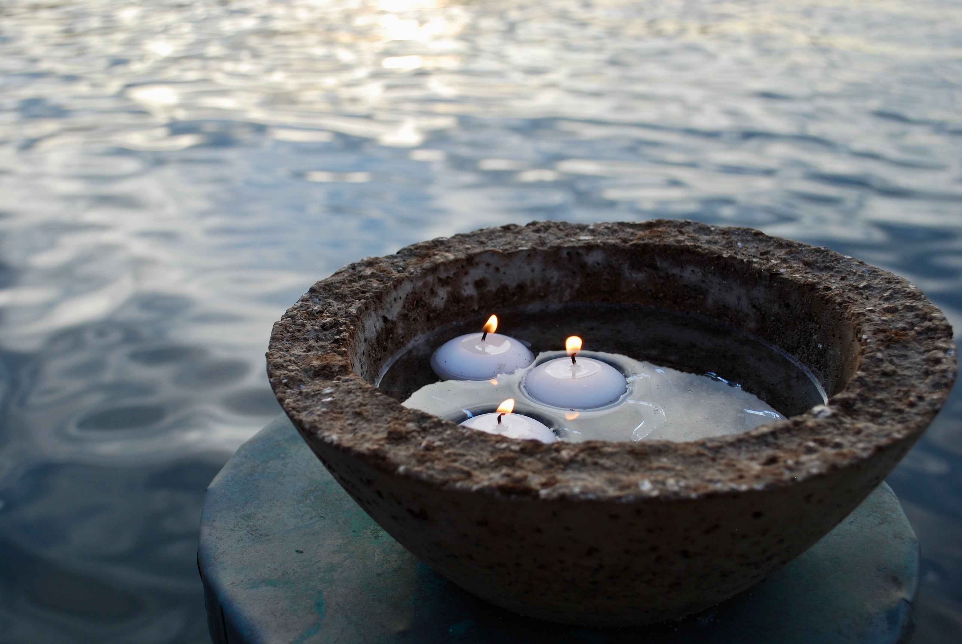 Ceramic bowl with floating candles on water
