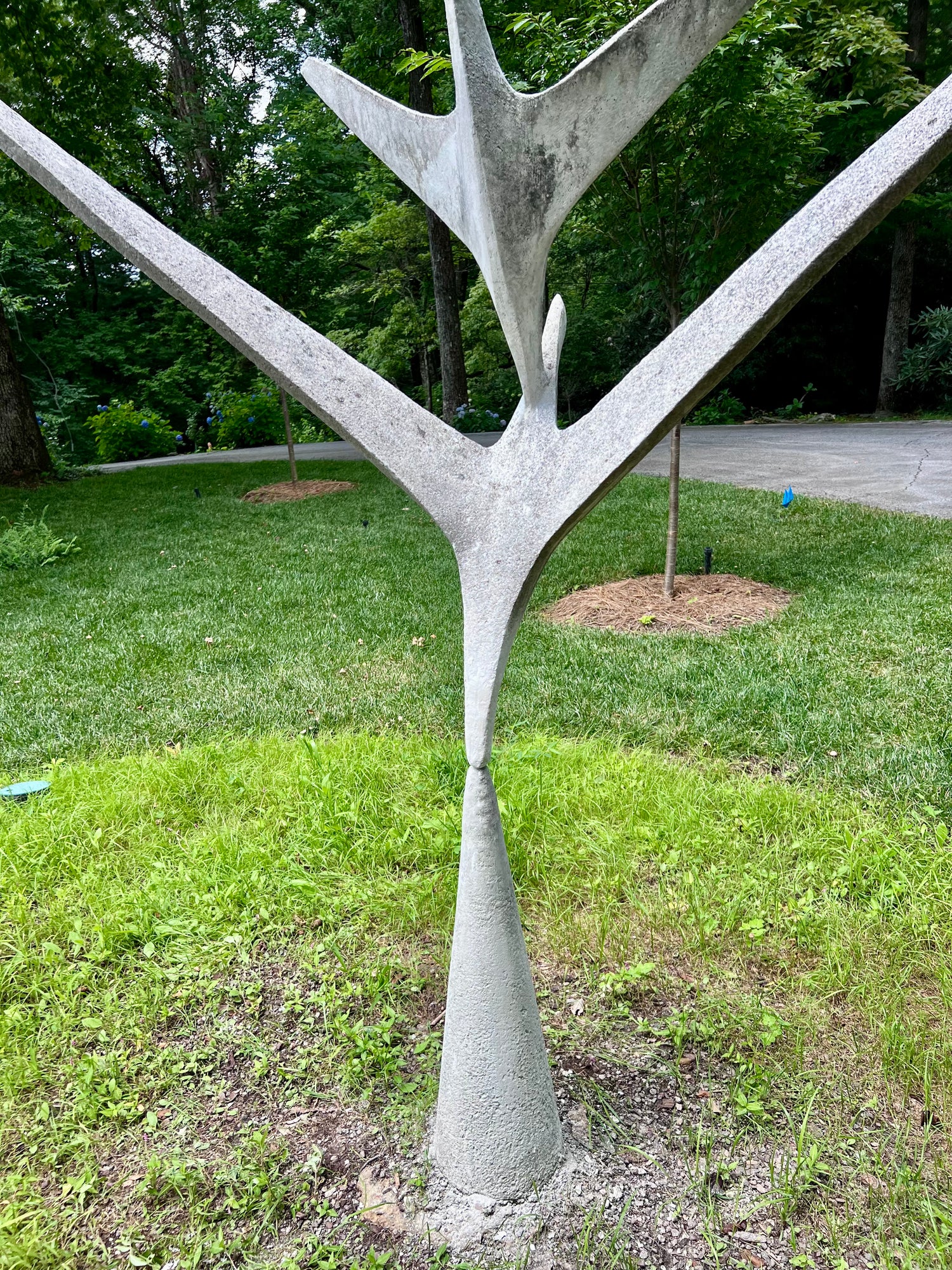Concrete tree sculpture in a park setting with grass and trees in the background