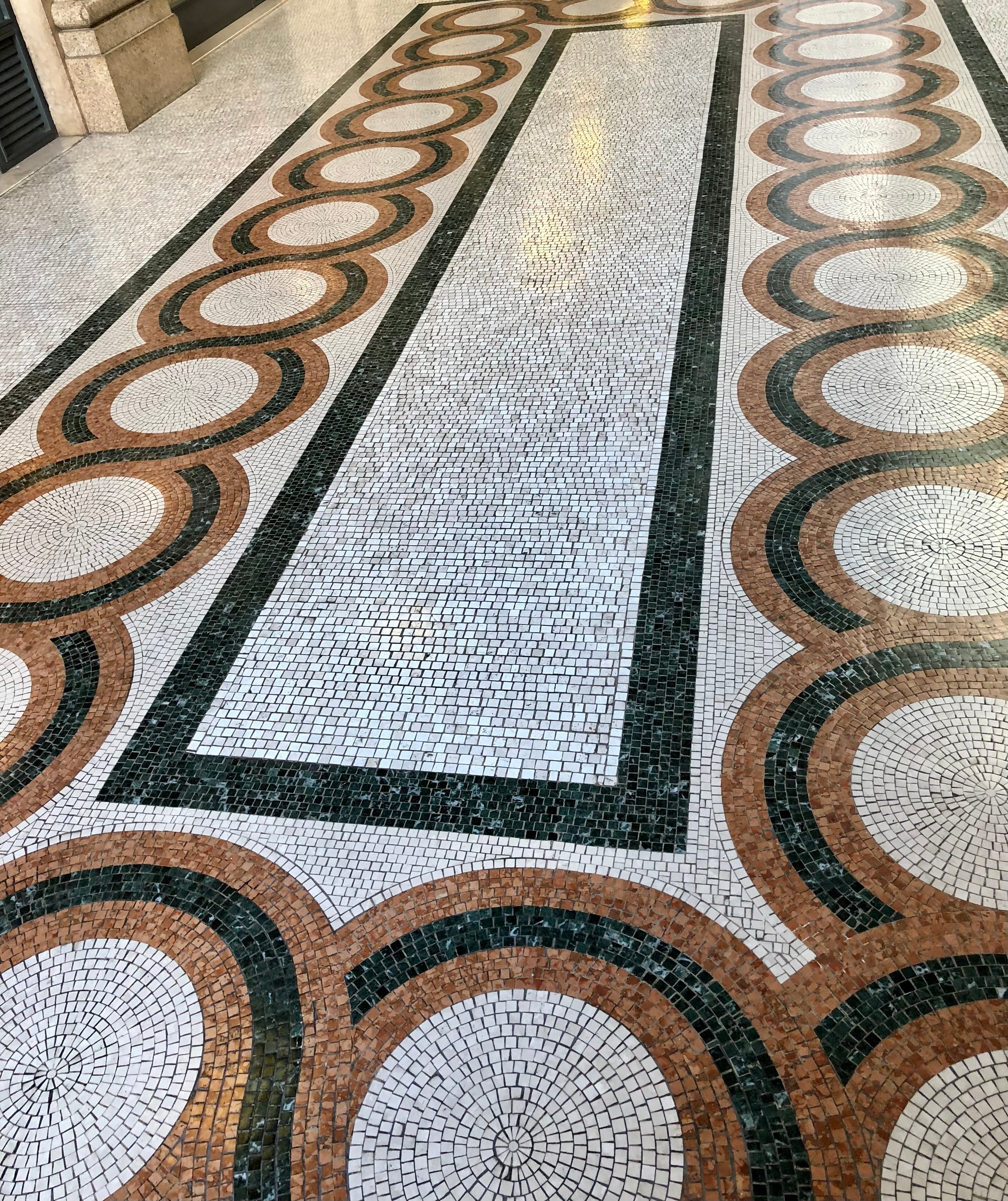 Decorative mosaic floor with circular patterns in a patterned room.