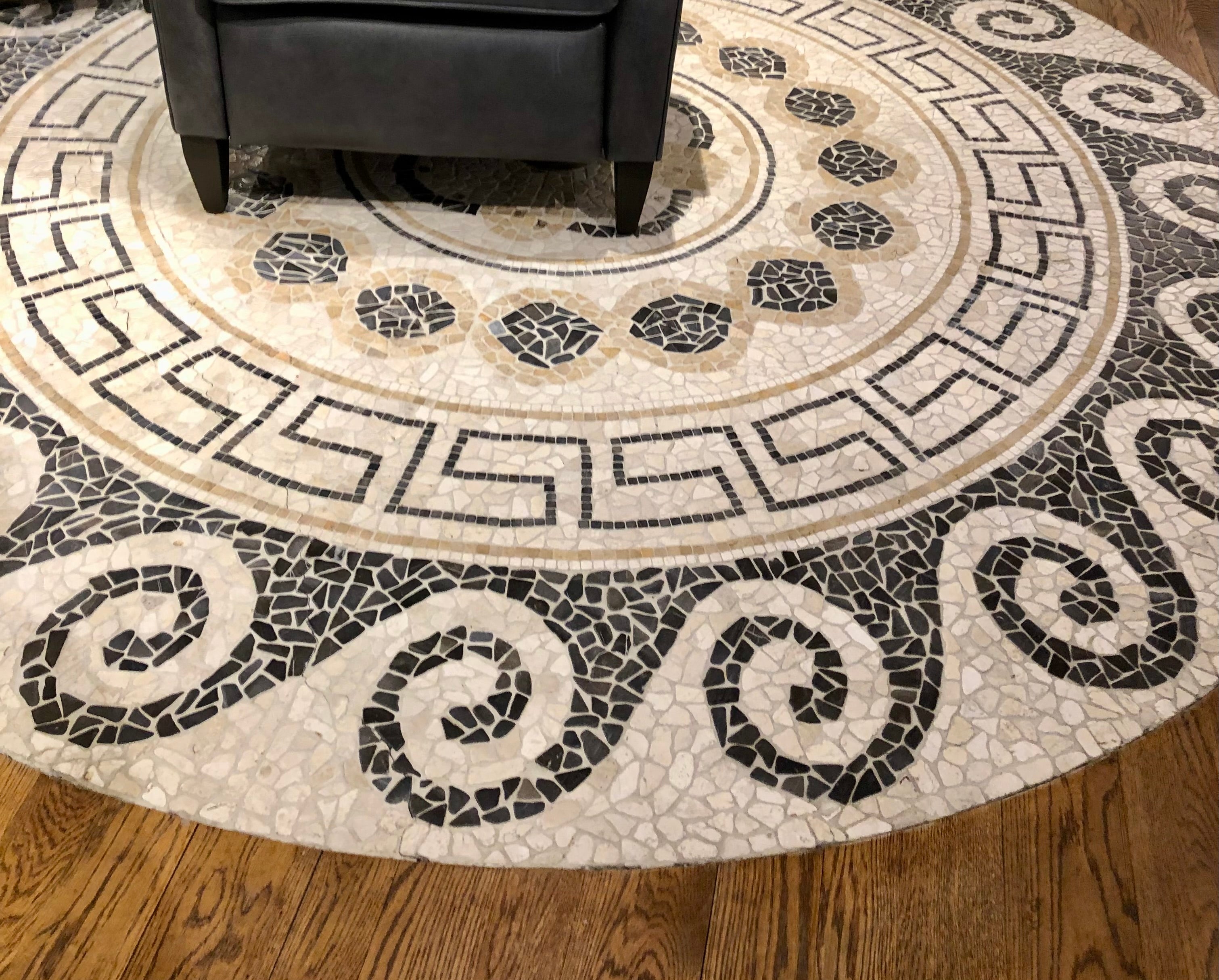 Round mosaic rug with intricate patterns on a wooden floor