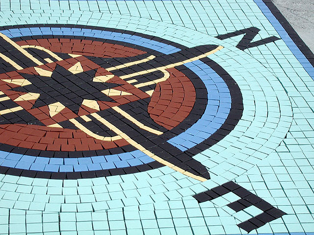Mosaic design with compass directions on a tiled surface