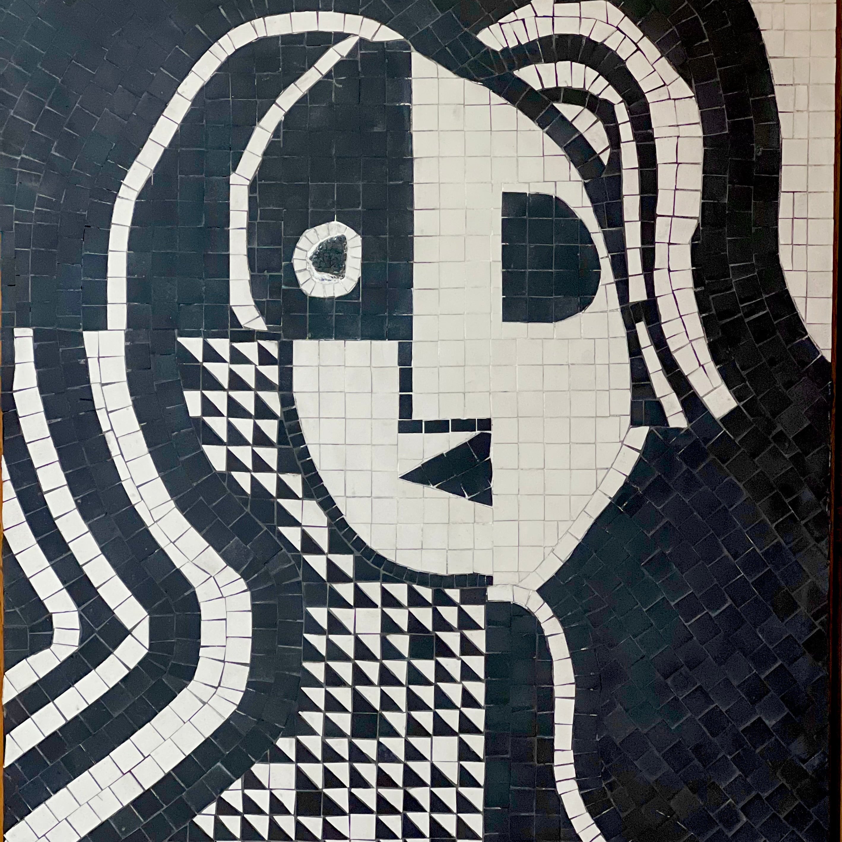 Mosaic artwork of a stylized face with geometric patterns on a dark background