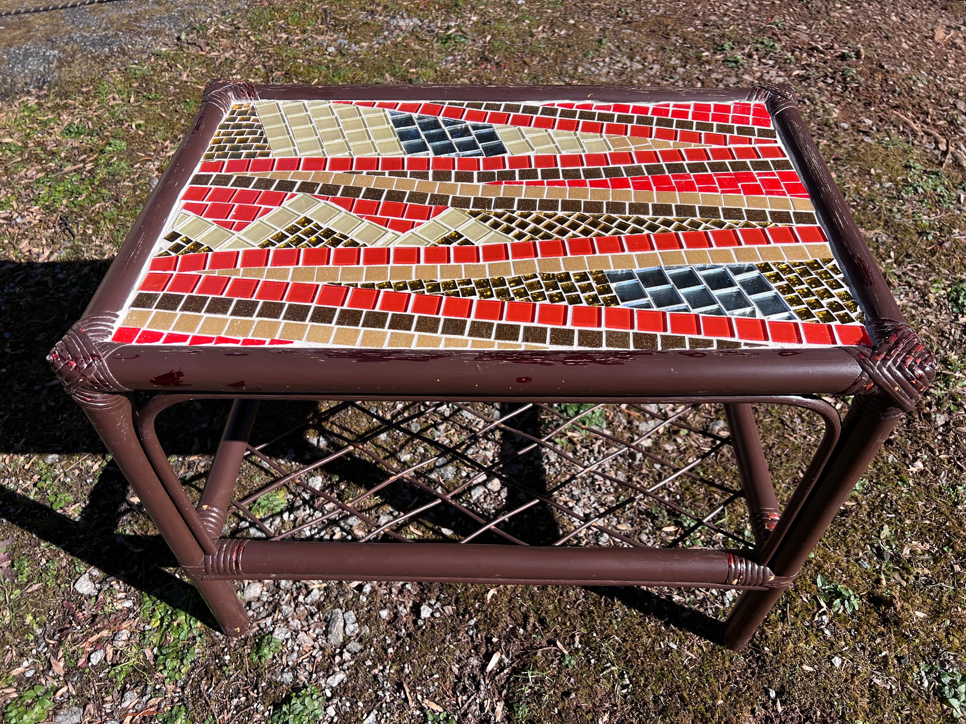 Mosaic table with a colorful design on a grassy background