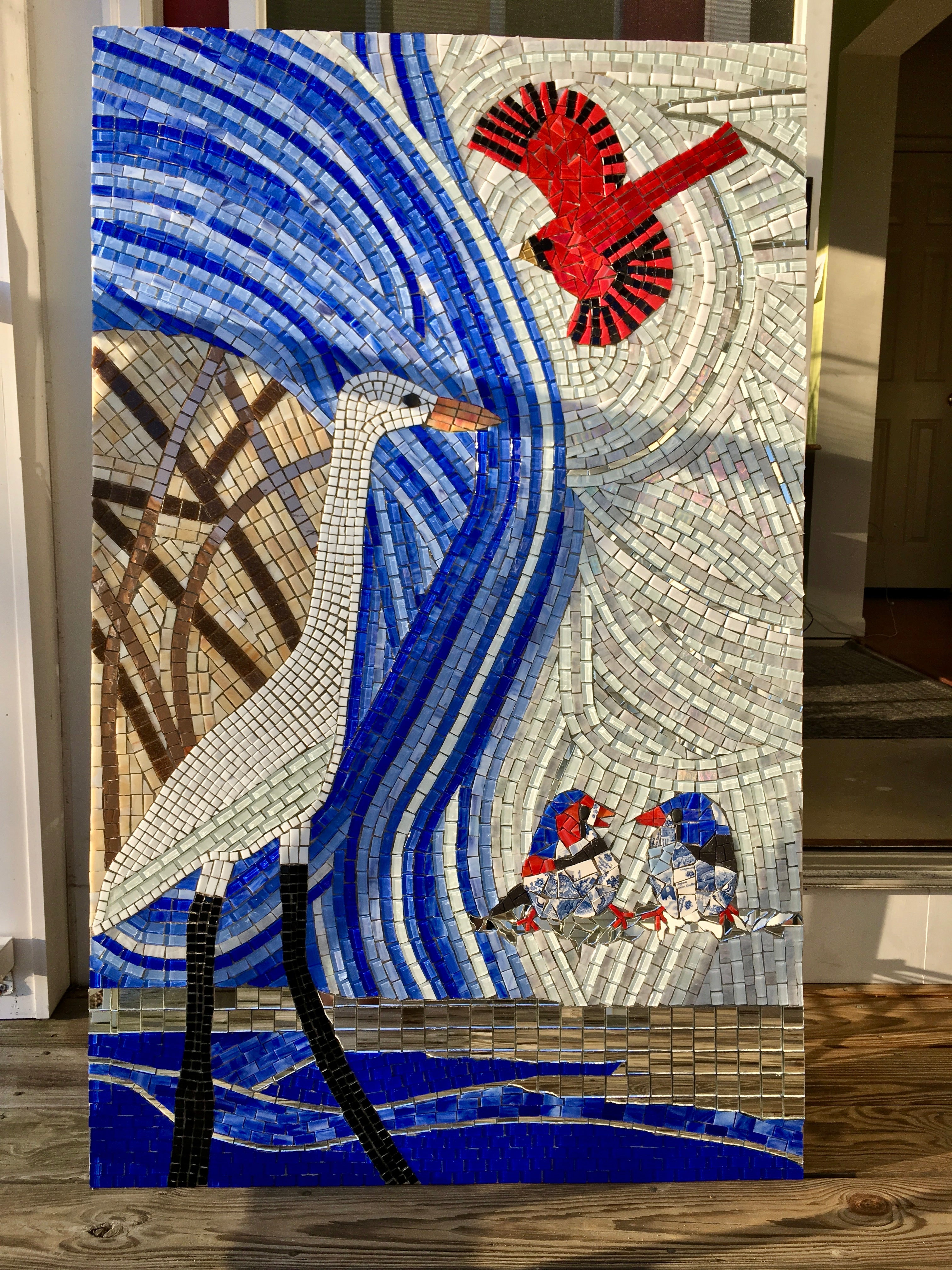 Mosaic artwork with birds and abstract patterns on a wooden floor.