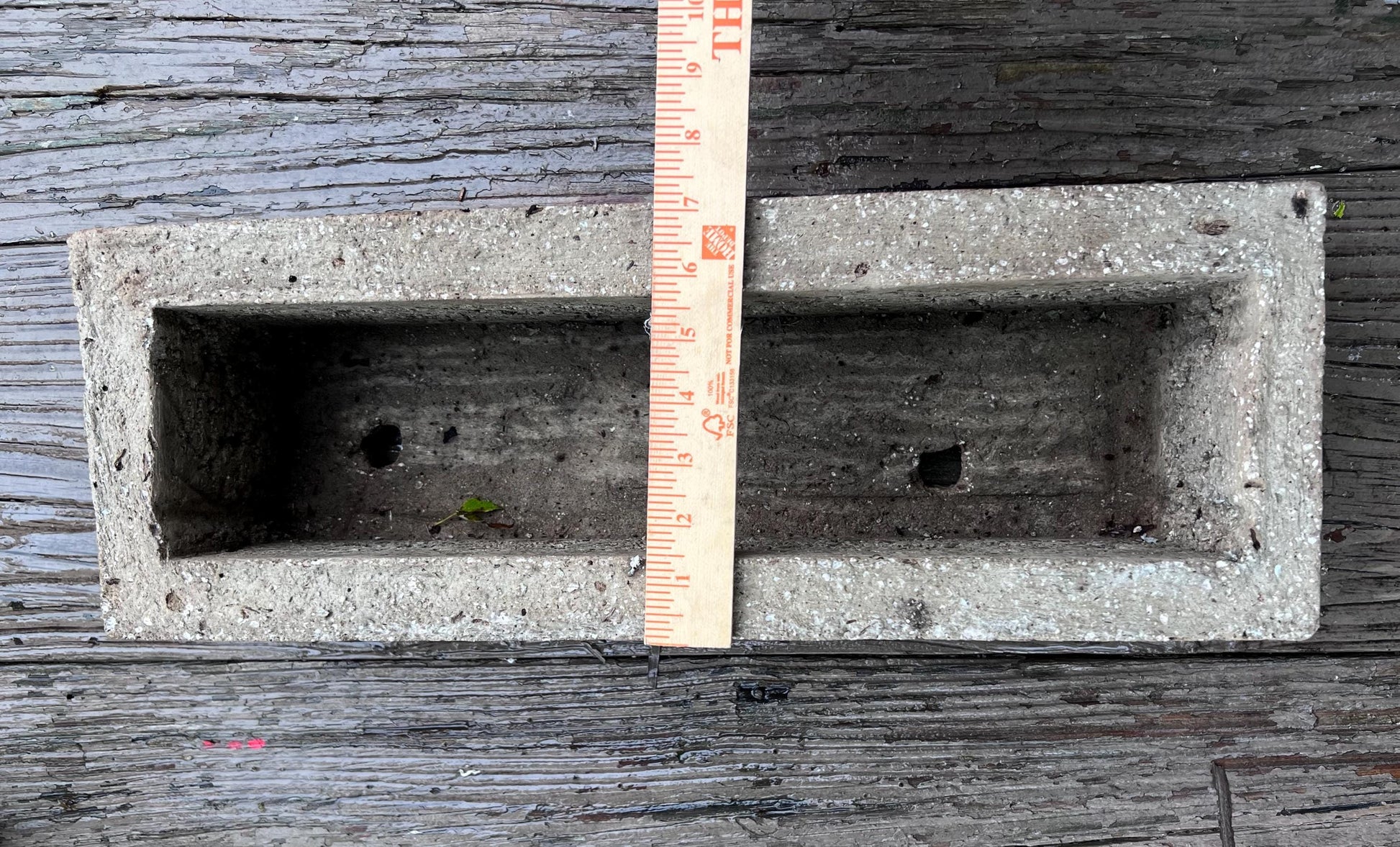 Concrete block with a ruler for scale on a wooden surface