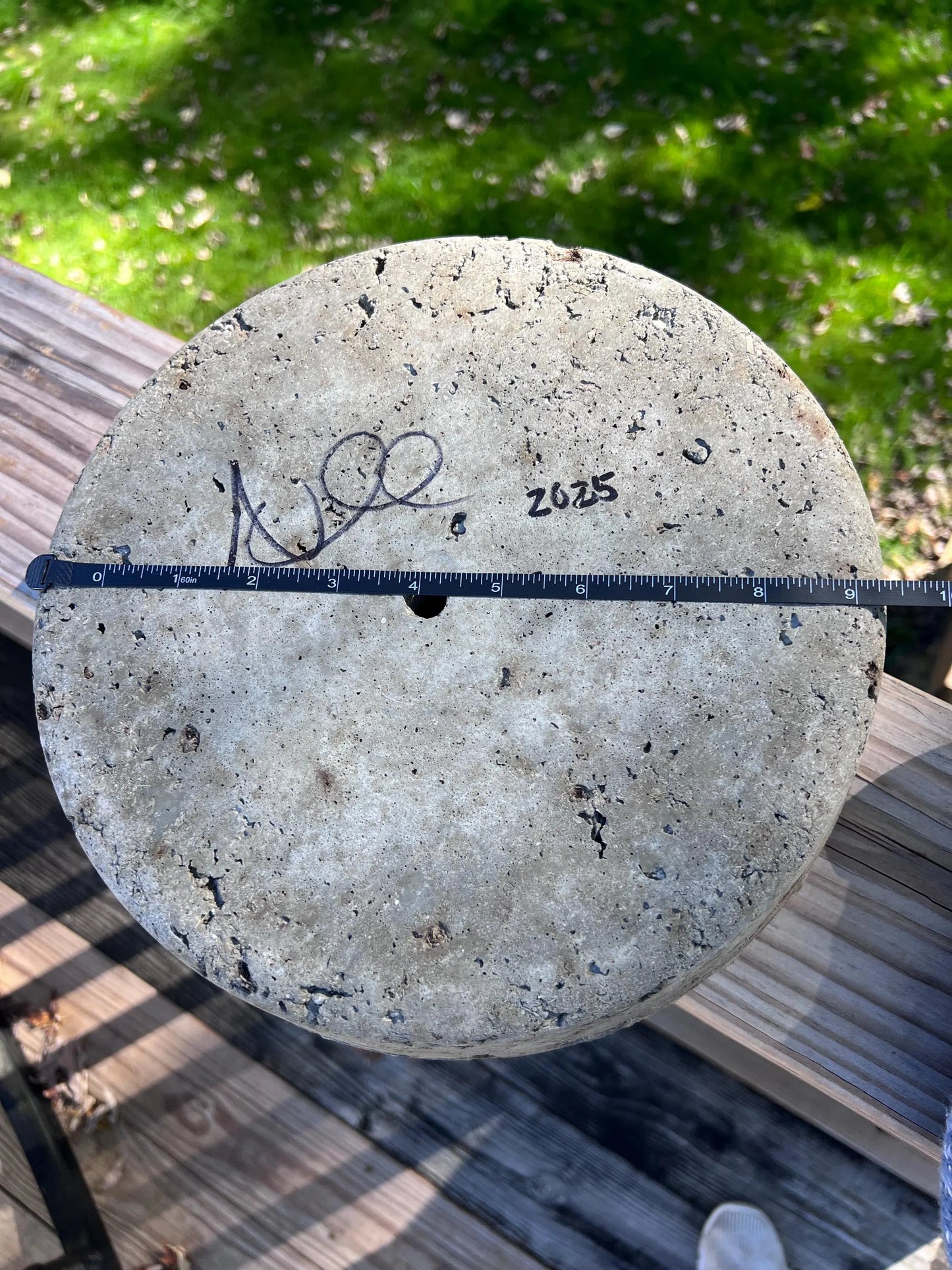 Concrete disk with a ruler for scale on a wooden surface