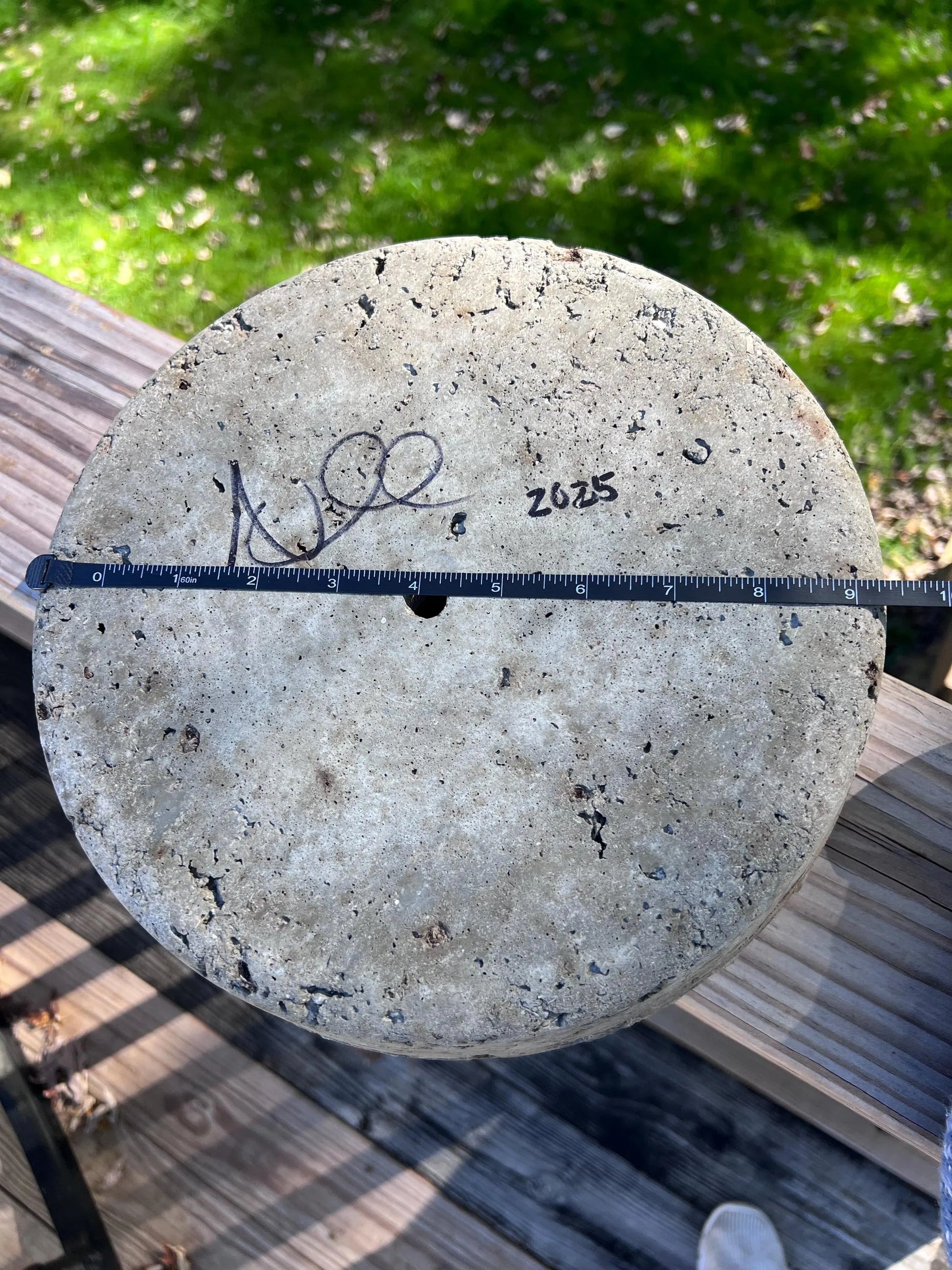 Concrete disk with a ruler for scale on a wooden surface