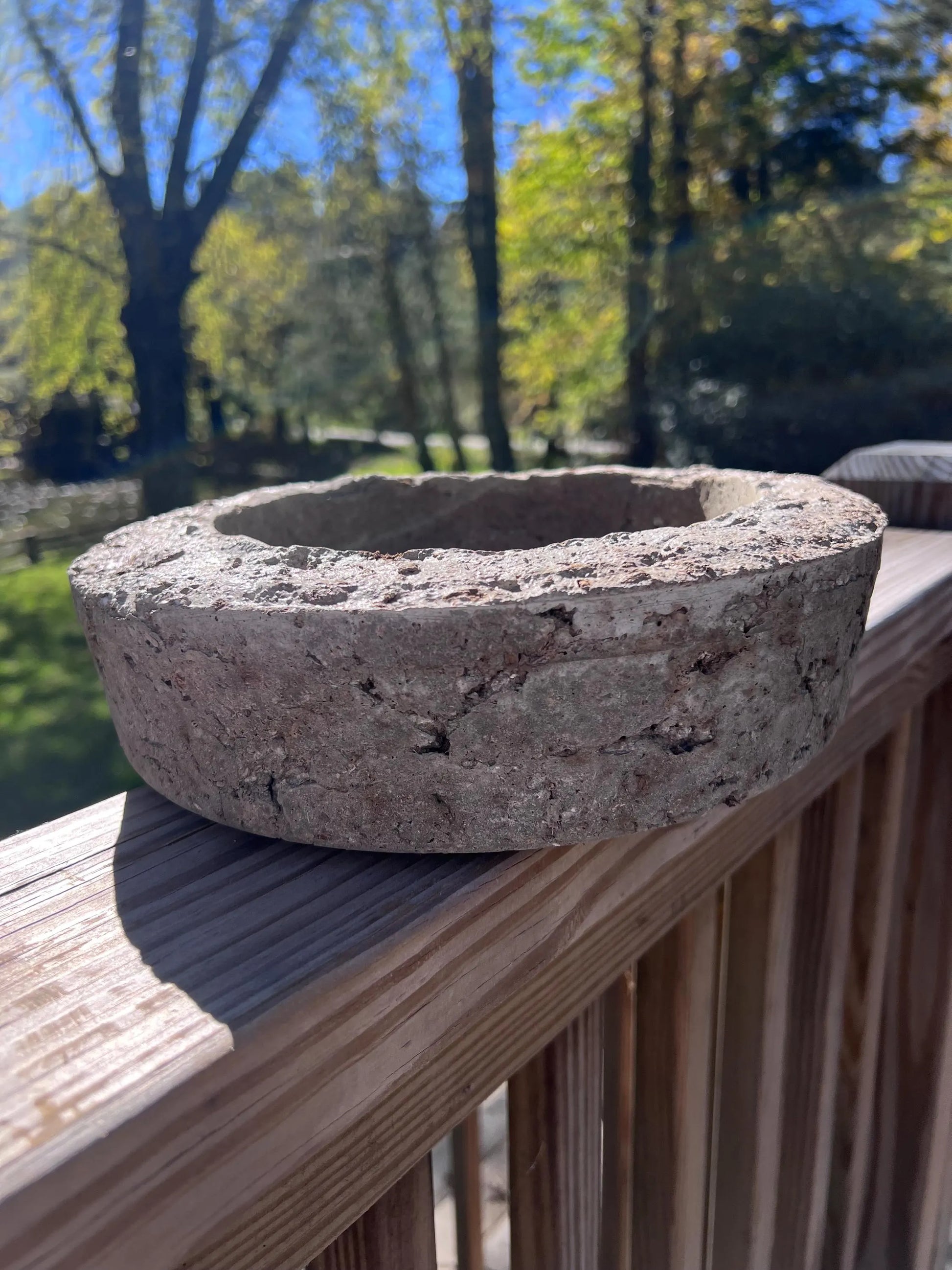Concrete block on a wooden deck with trees in the background