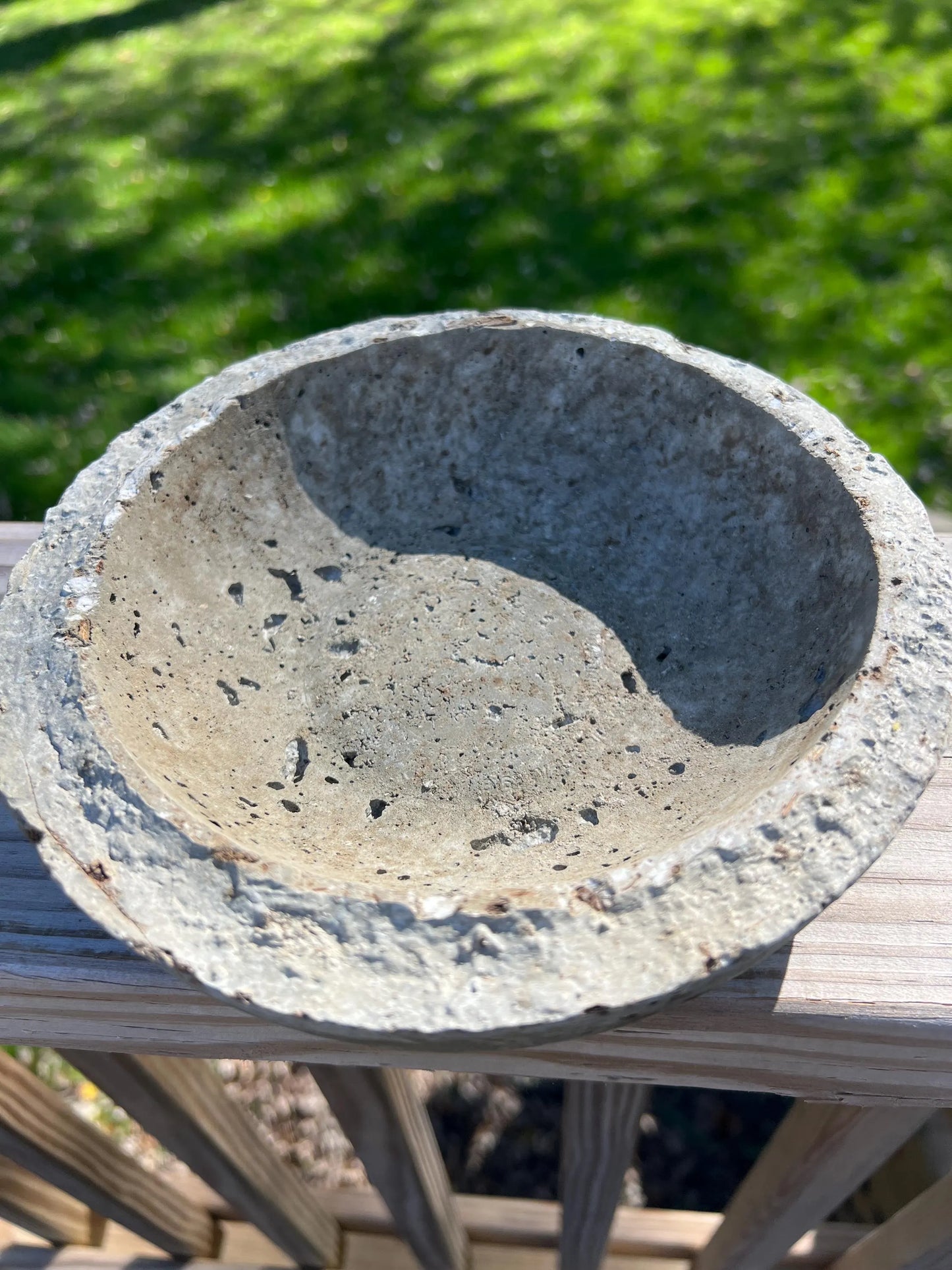 Concrete bowl on a wooden surface with a blurred green background