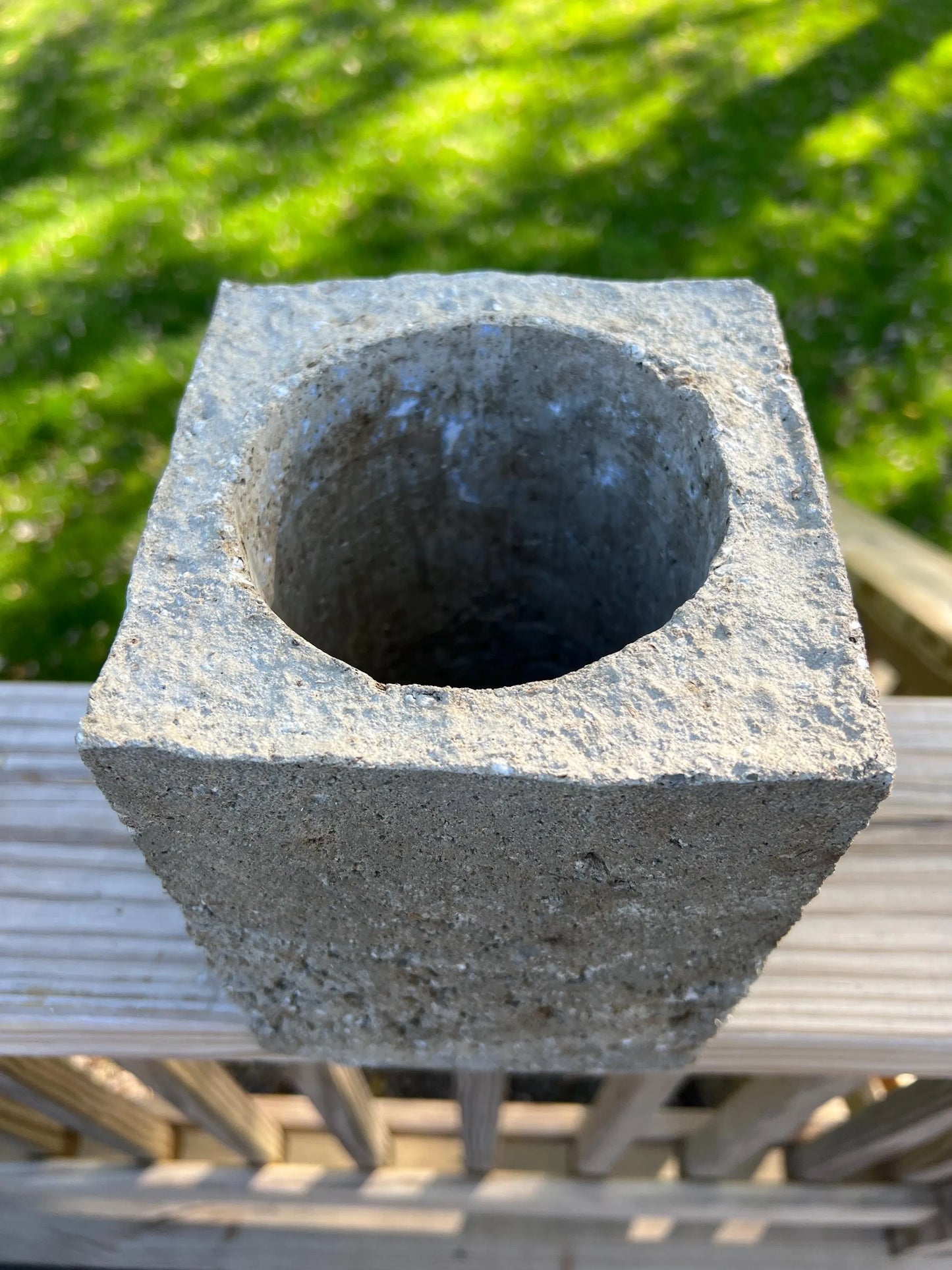 Cement block with a circular hole on a metal surface with grass in the background