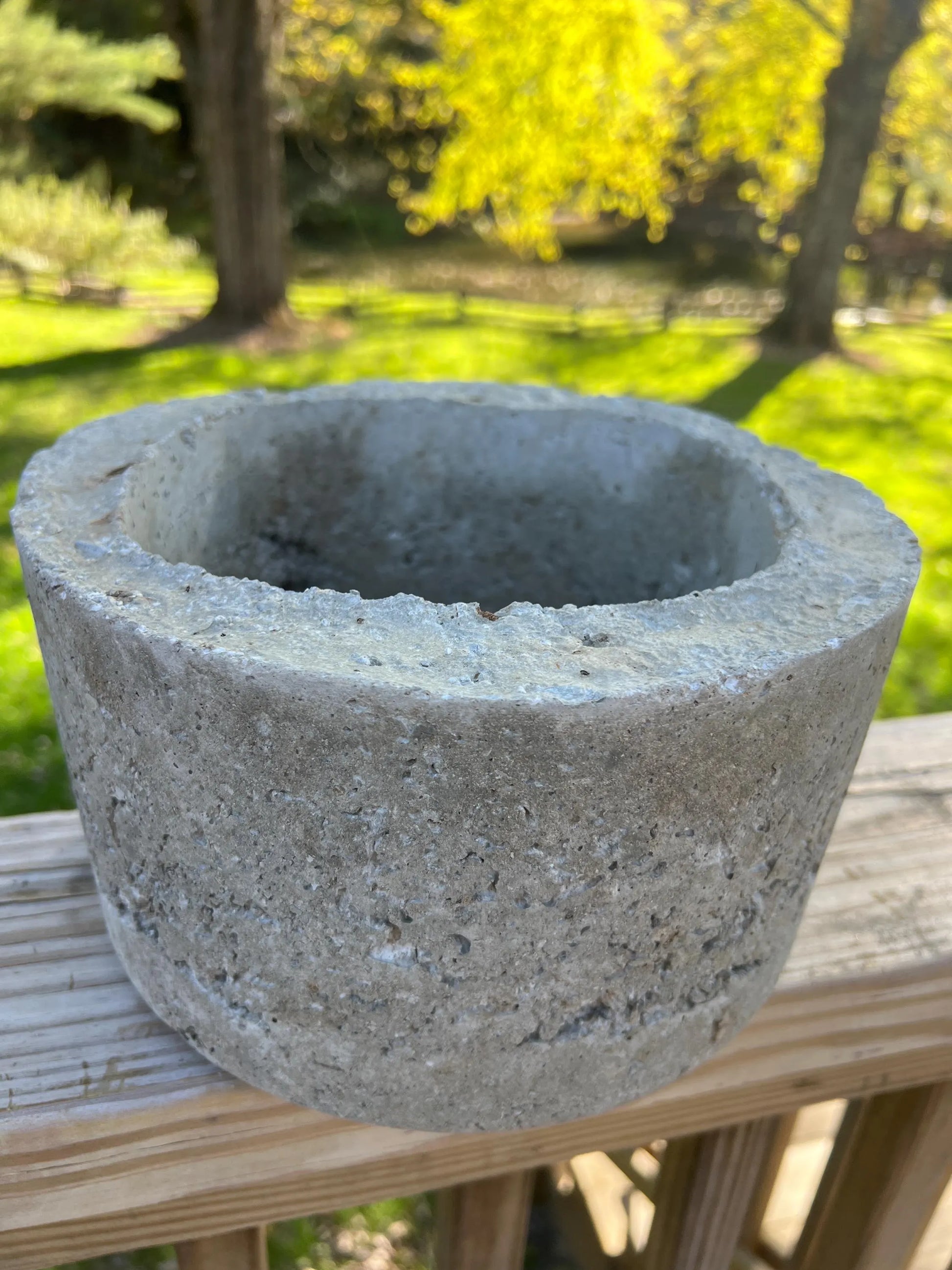 Concrete planter on a wooden surface with a blurred natural background