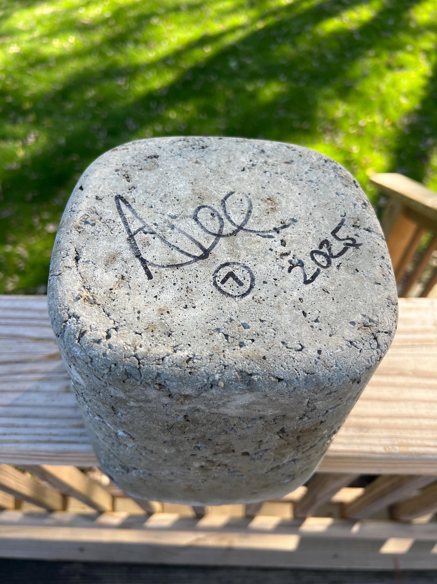 Concrete block with signatures and date on a wooden surface