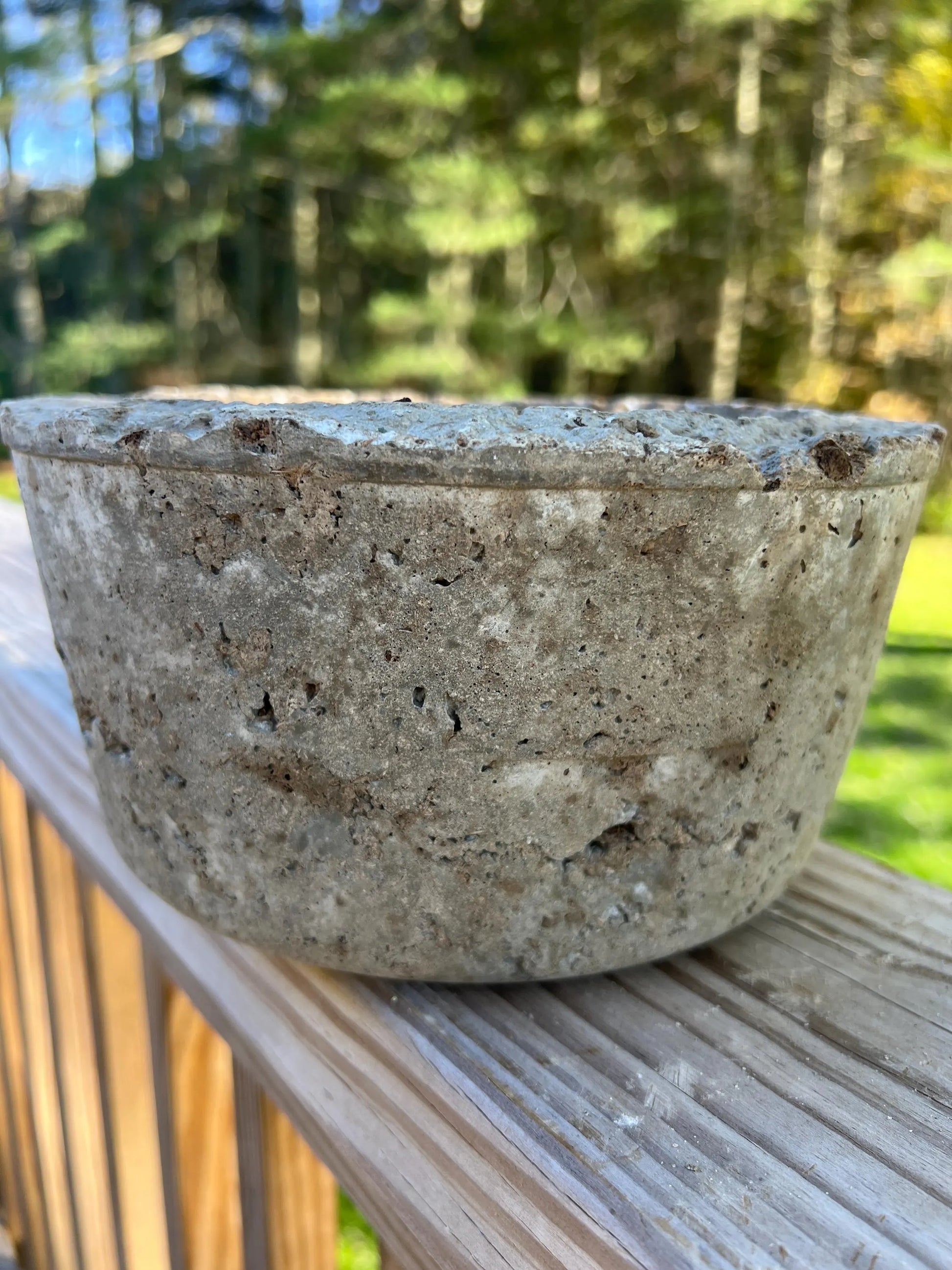 Concrete bowl on a wooden surface with a natural background