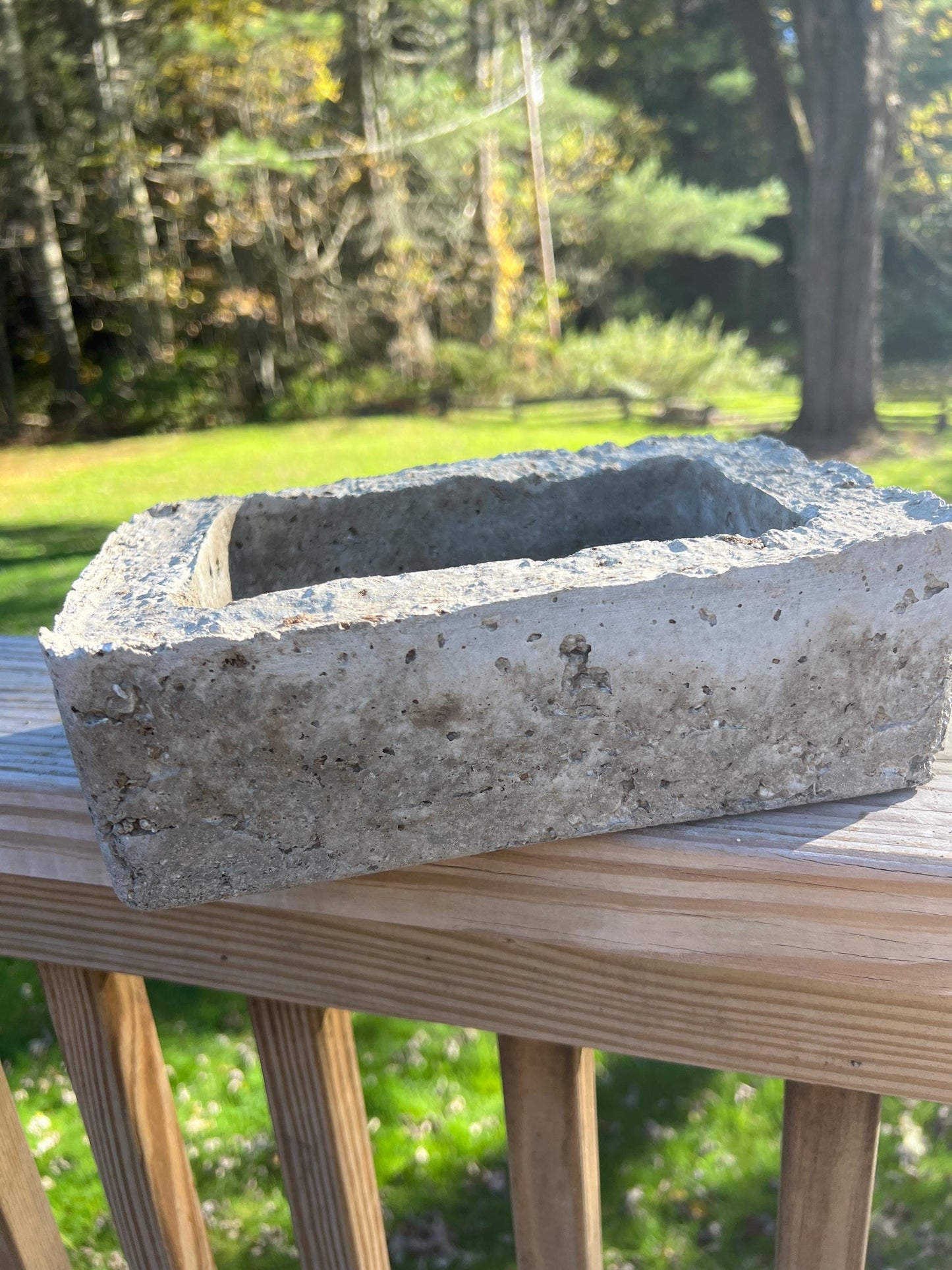 Concrete block on a wooden deck with a blurred natural background