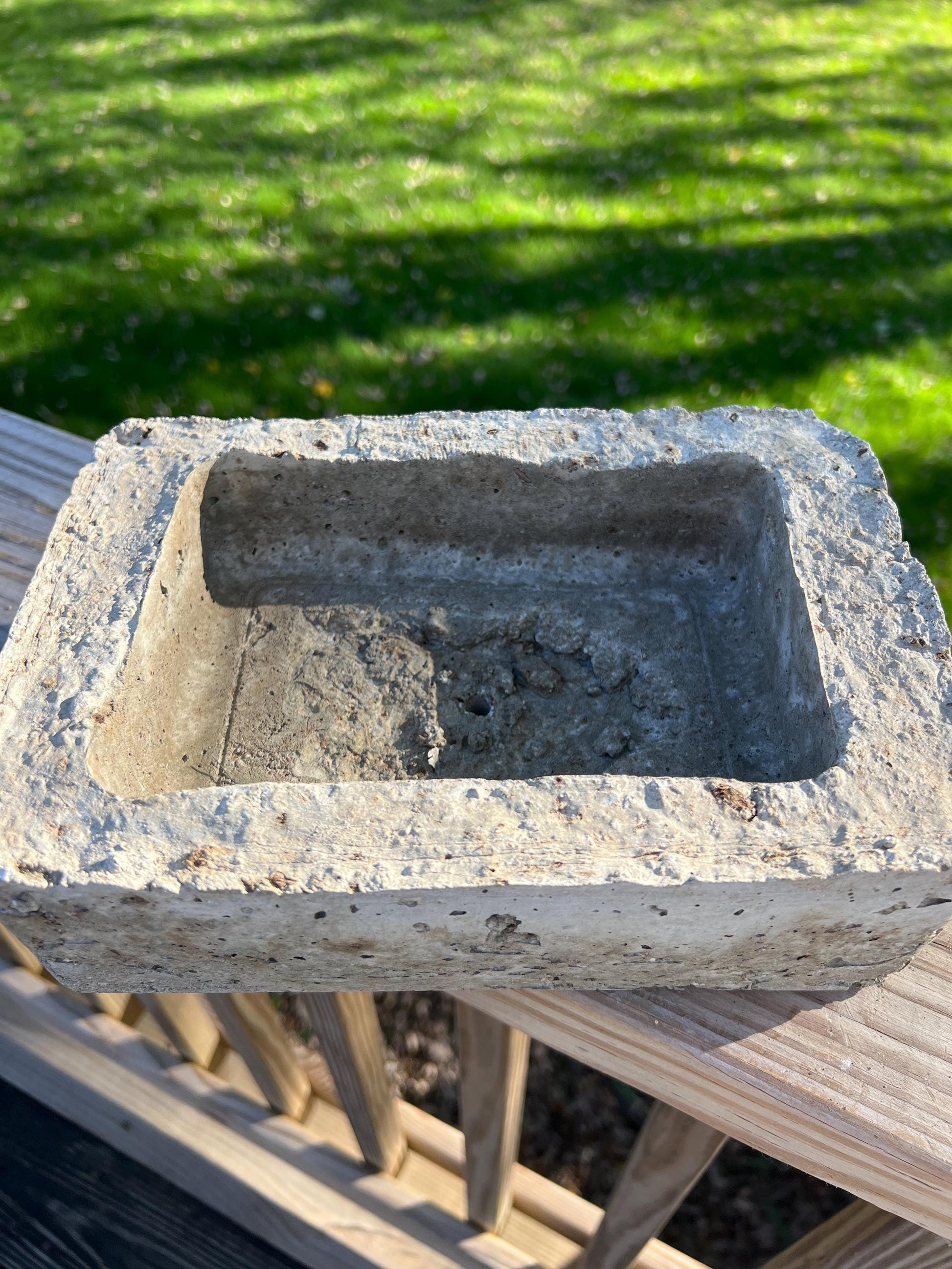 Concrete block on a wooden surface with grass in the background