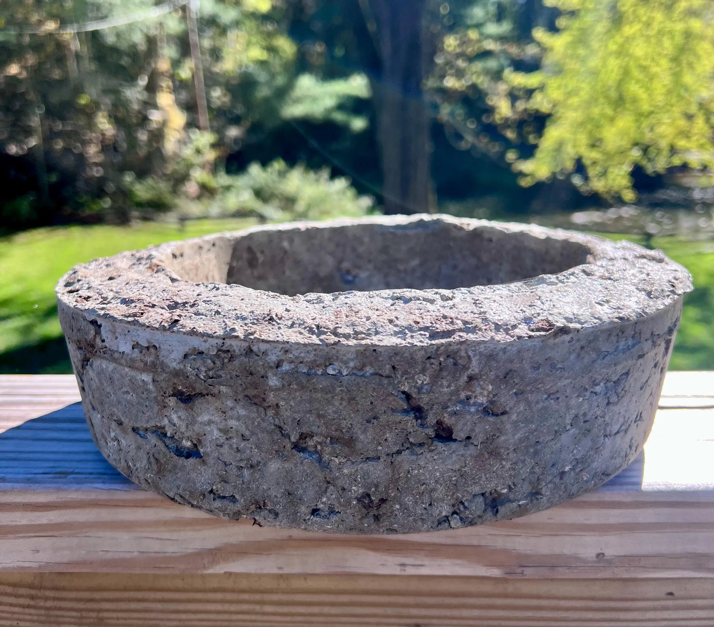 Concrete basin on a wooden surface with a blurred natural background