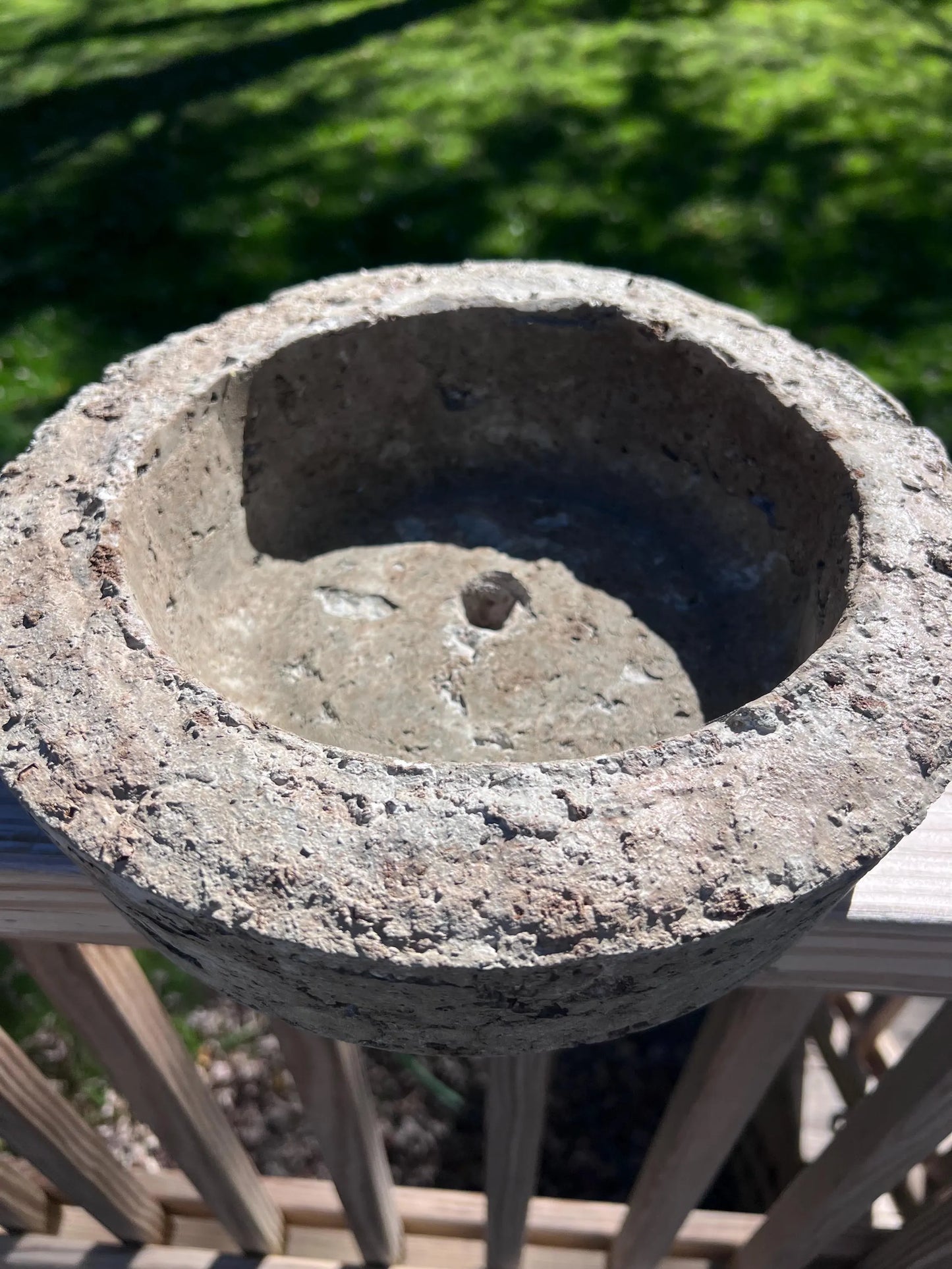 Concrete birdbath with a textured surface on a blurred green background