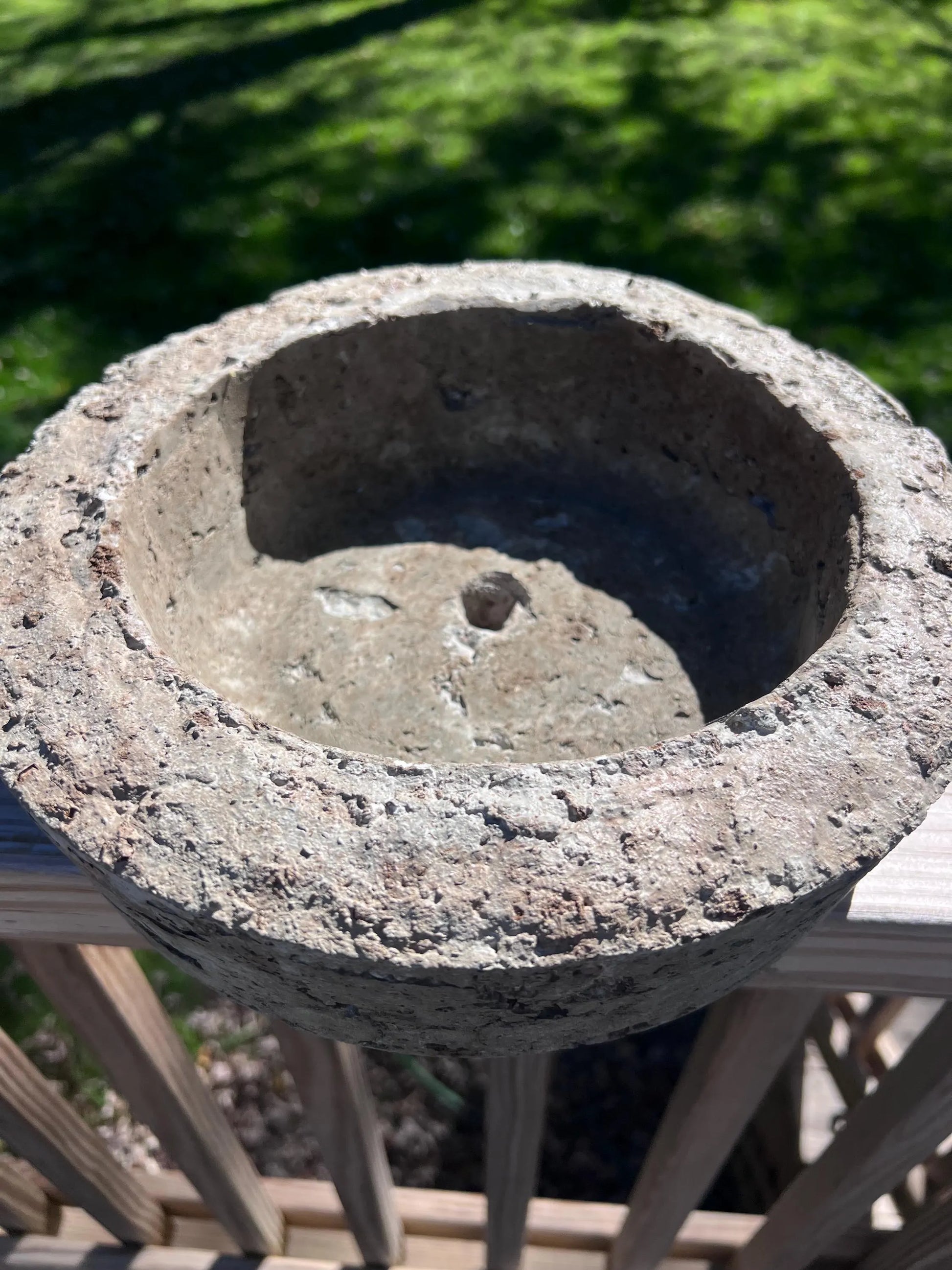 Concrete birdbath with a textured surface on a blurred green background