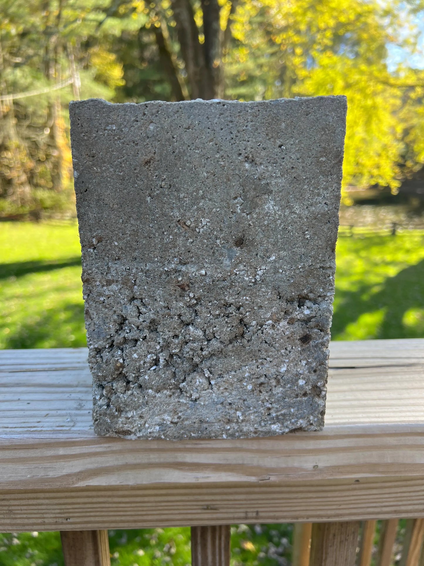 Concrete block on a wooden surface with a blurred natural background