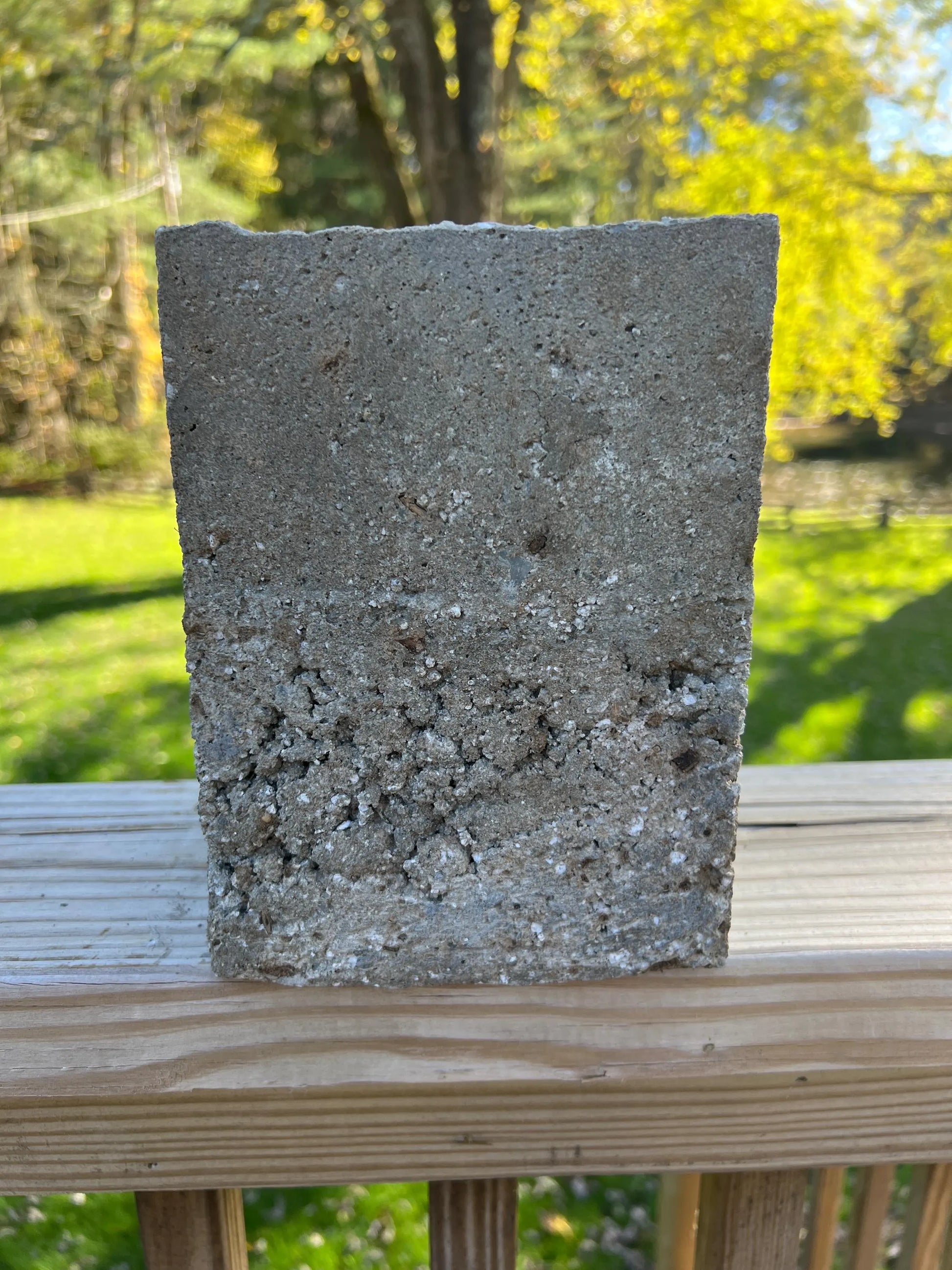 Concrete block on a wooden surface with a blurred natural background