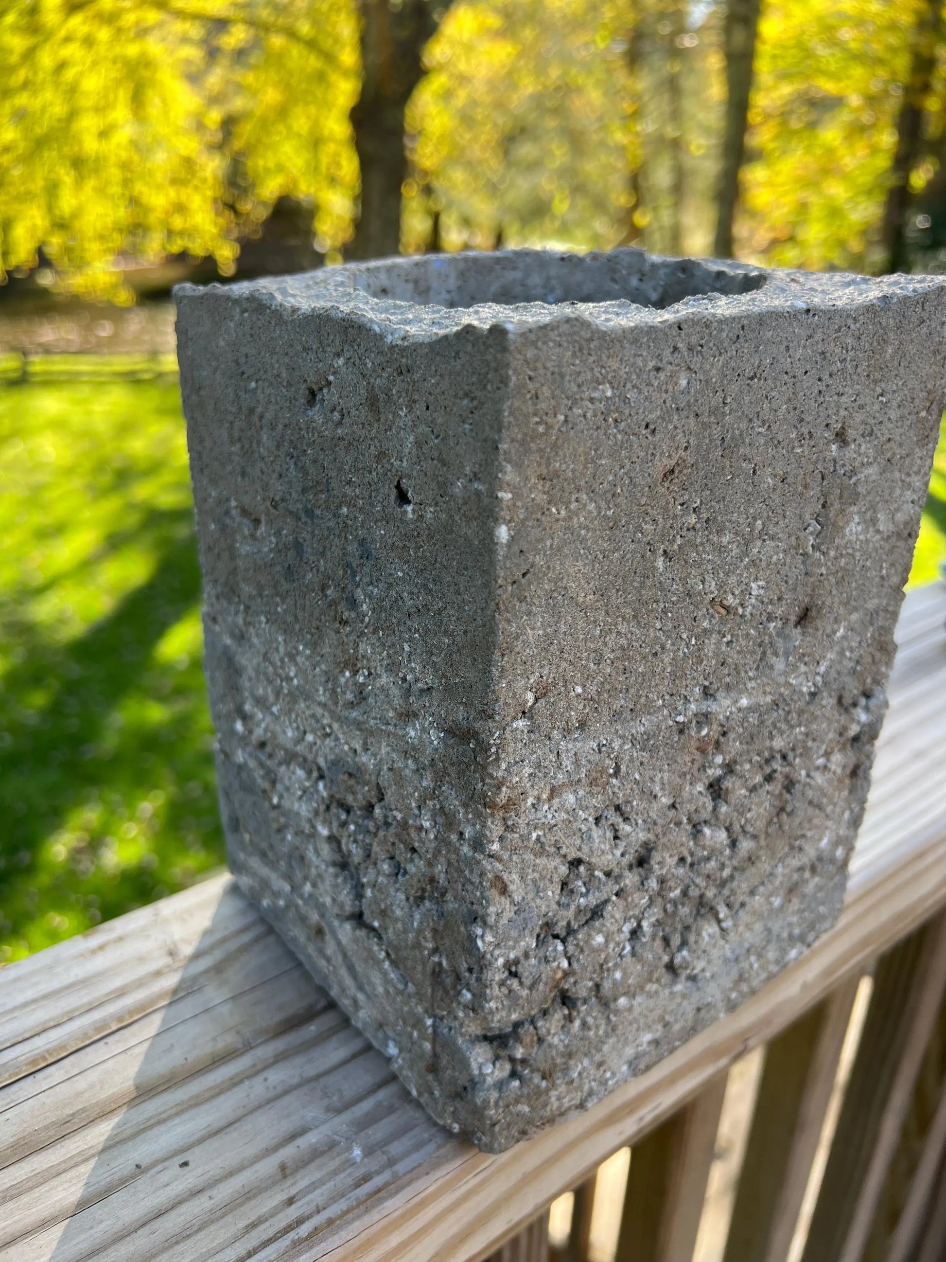 Concrete block on a wooden surface with a blurred natural background