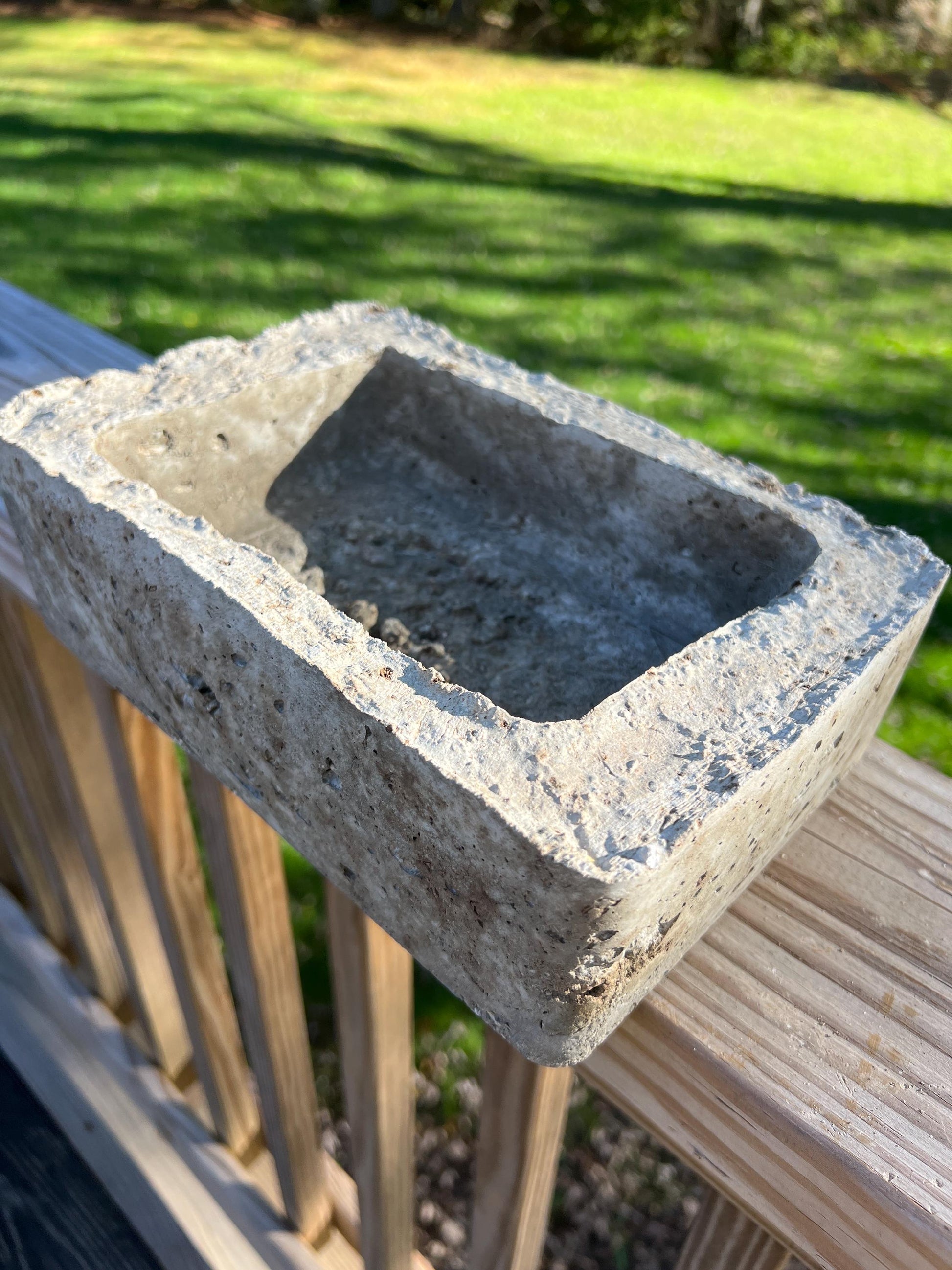Concrete sink on a wooden surface with grass in the background