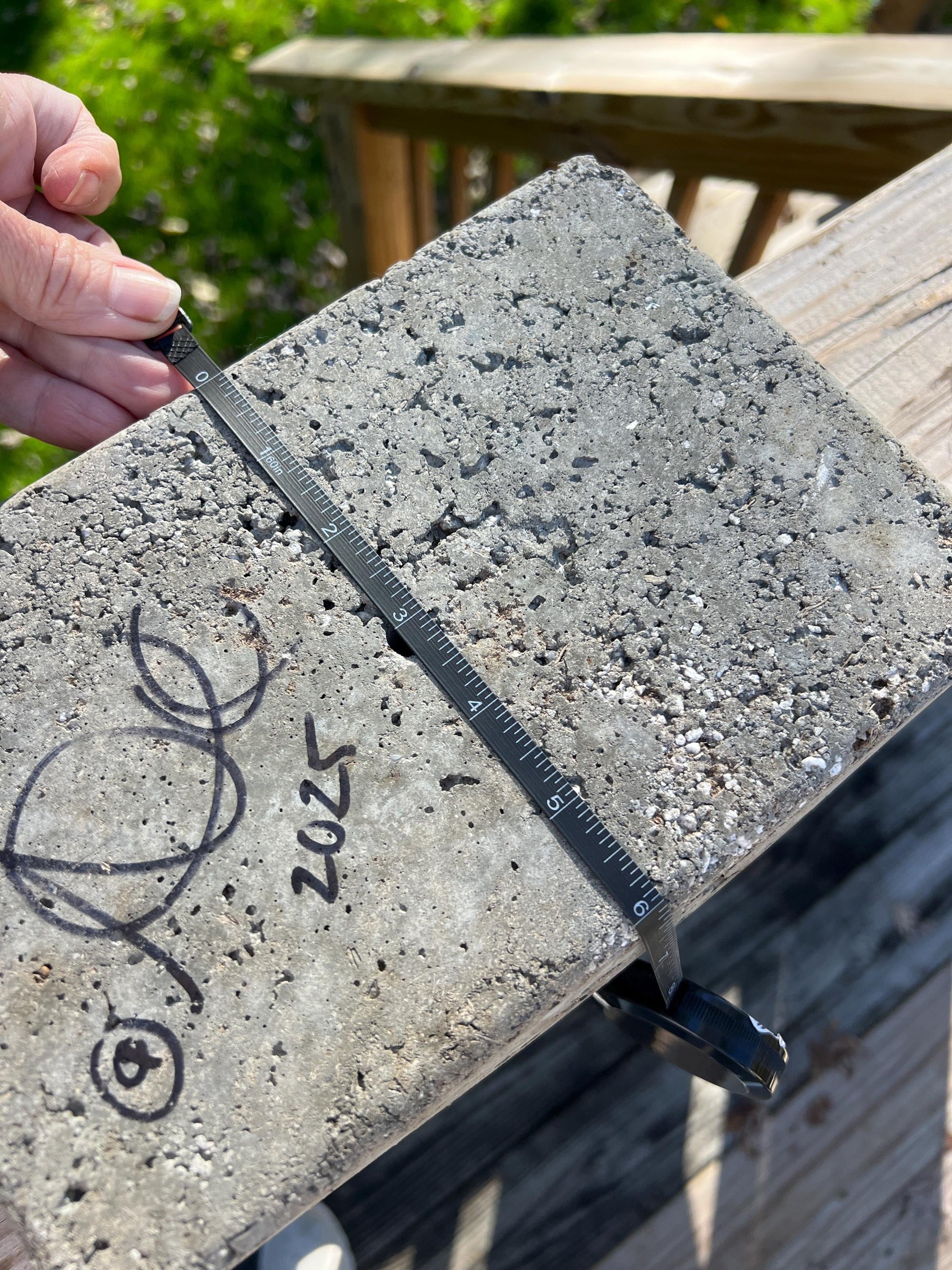 Concrete block with a ruler and signature, outdoors