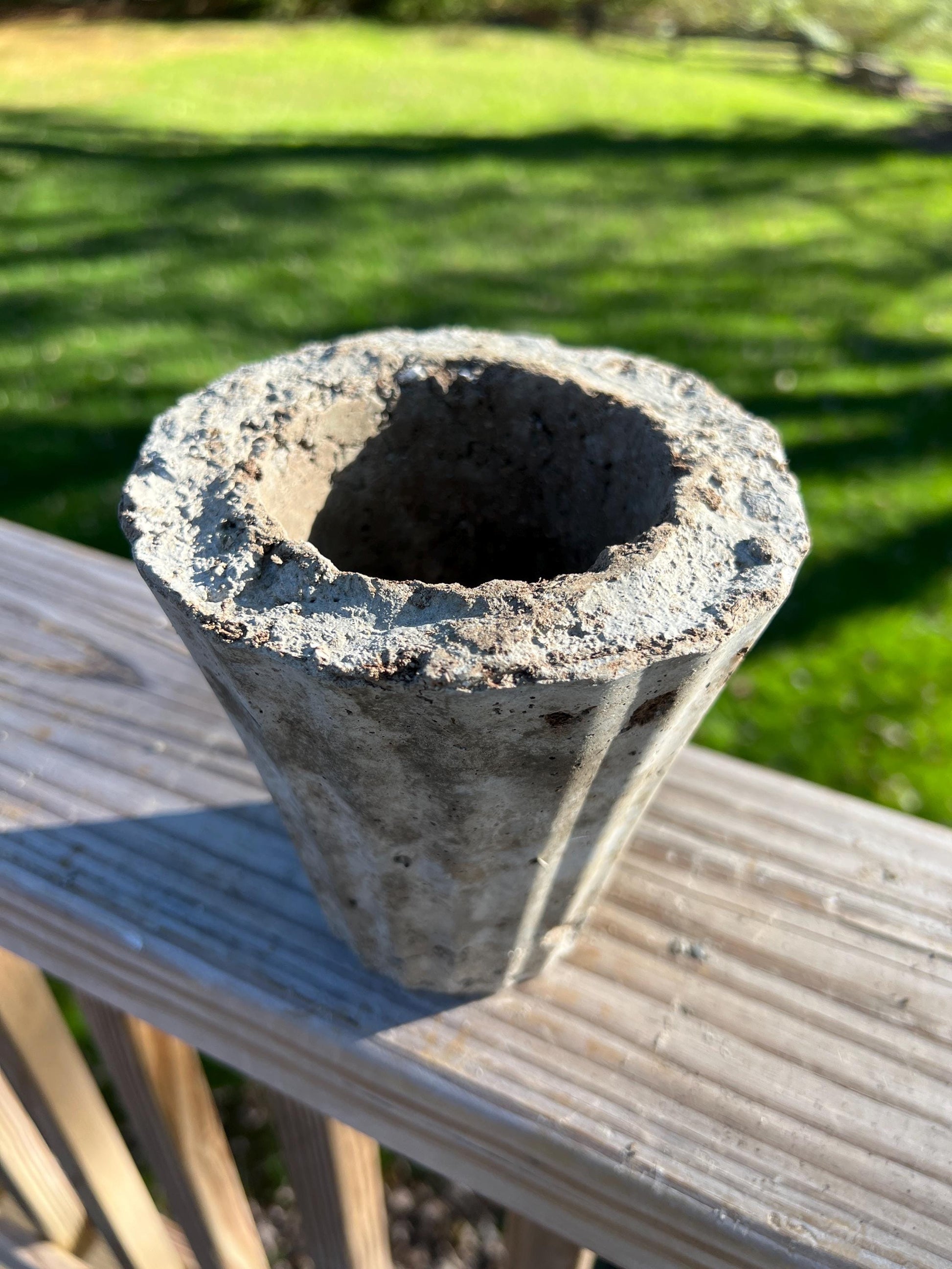 Concrete flower pot on a wooden surface with grass in the background
