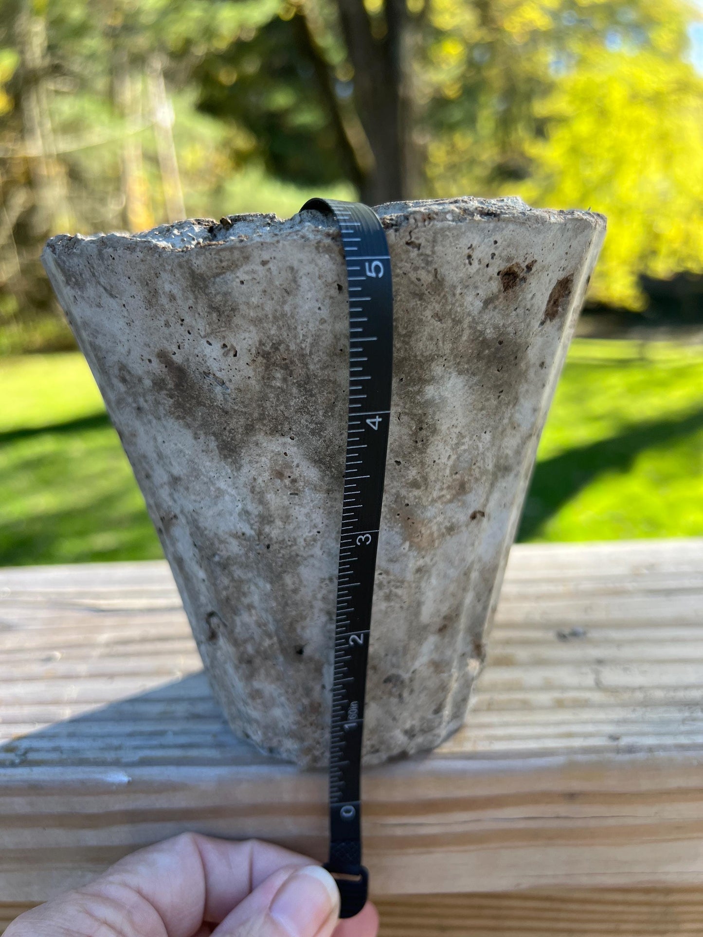 Concrete block with a ruler for scale against a blurred green outdoor background